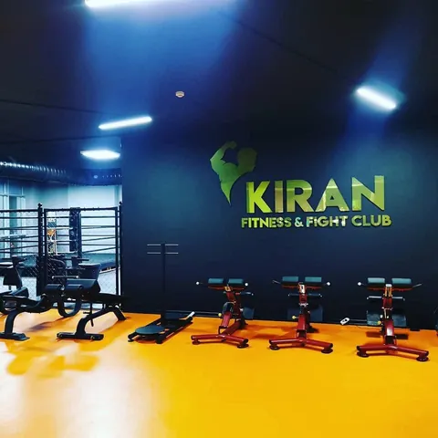 Duvarda Kıran Fitness & Fight Club logosu, turuncu zeminde makine sırası